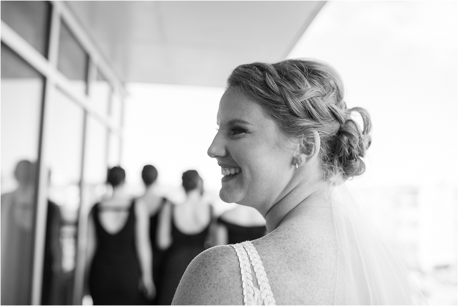 bride smiling right before showing bridesmaids her dress