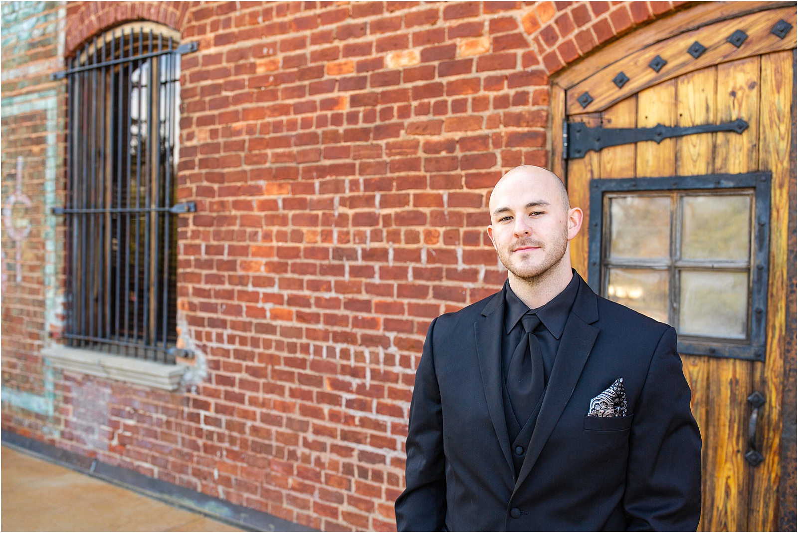 Groom in black suit and tie standing outside old cigar warehouse