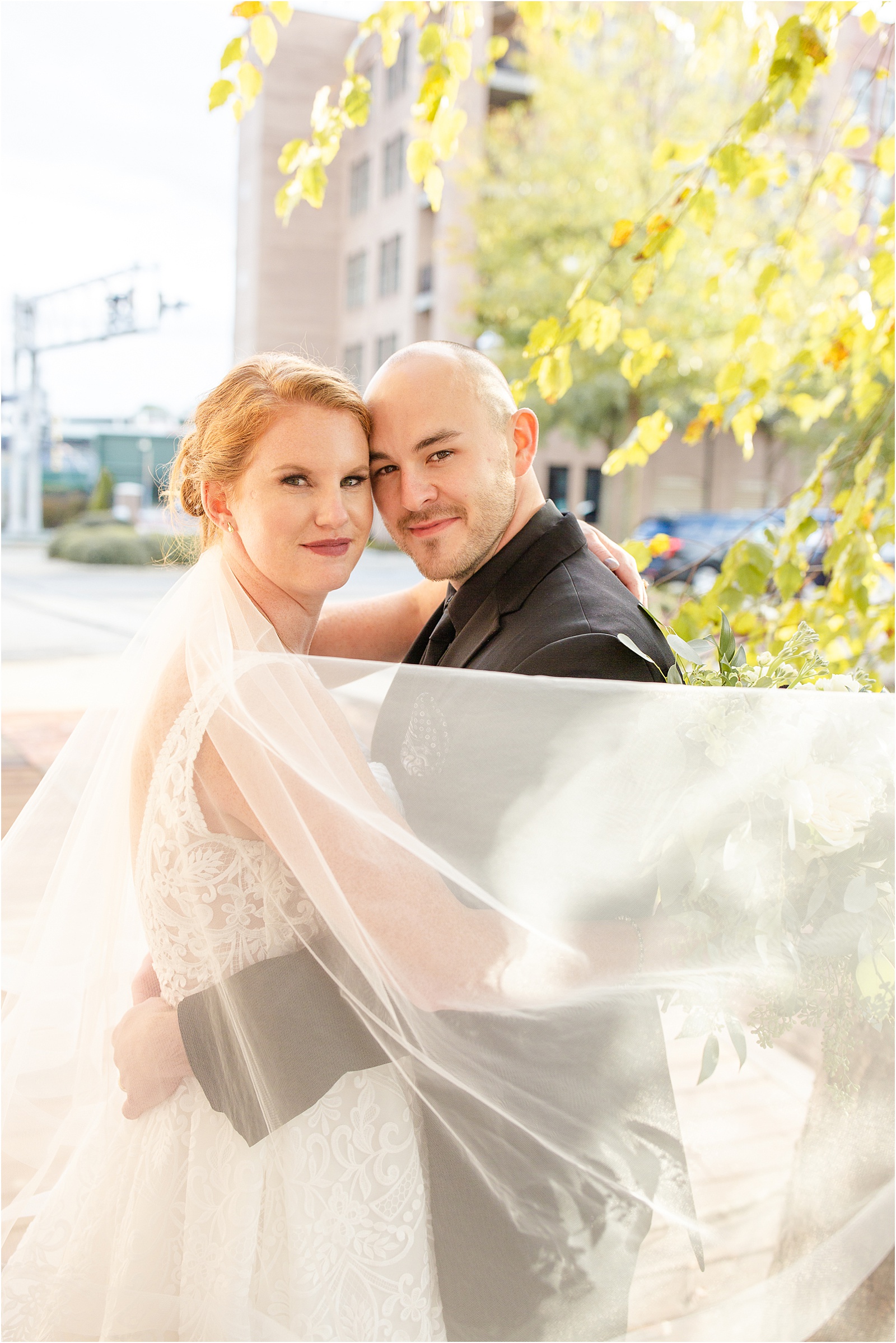 Just married couple looks at camera with veil blowing across