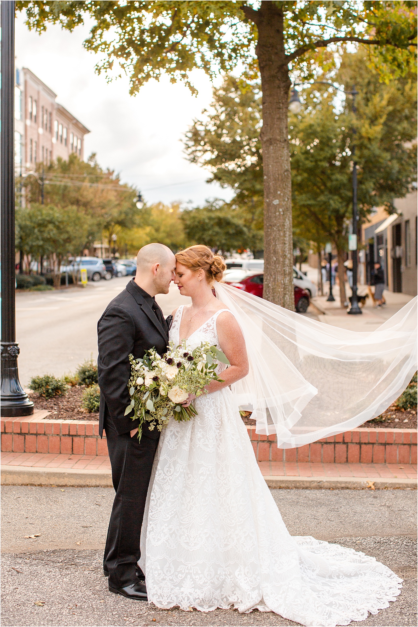 Bride and groom cuddle with eyes closed in street of Downtown Greenville