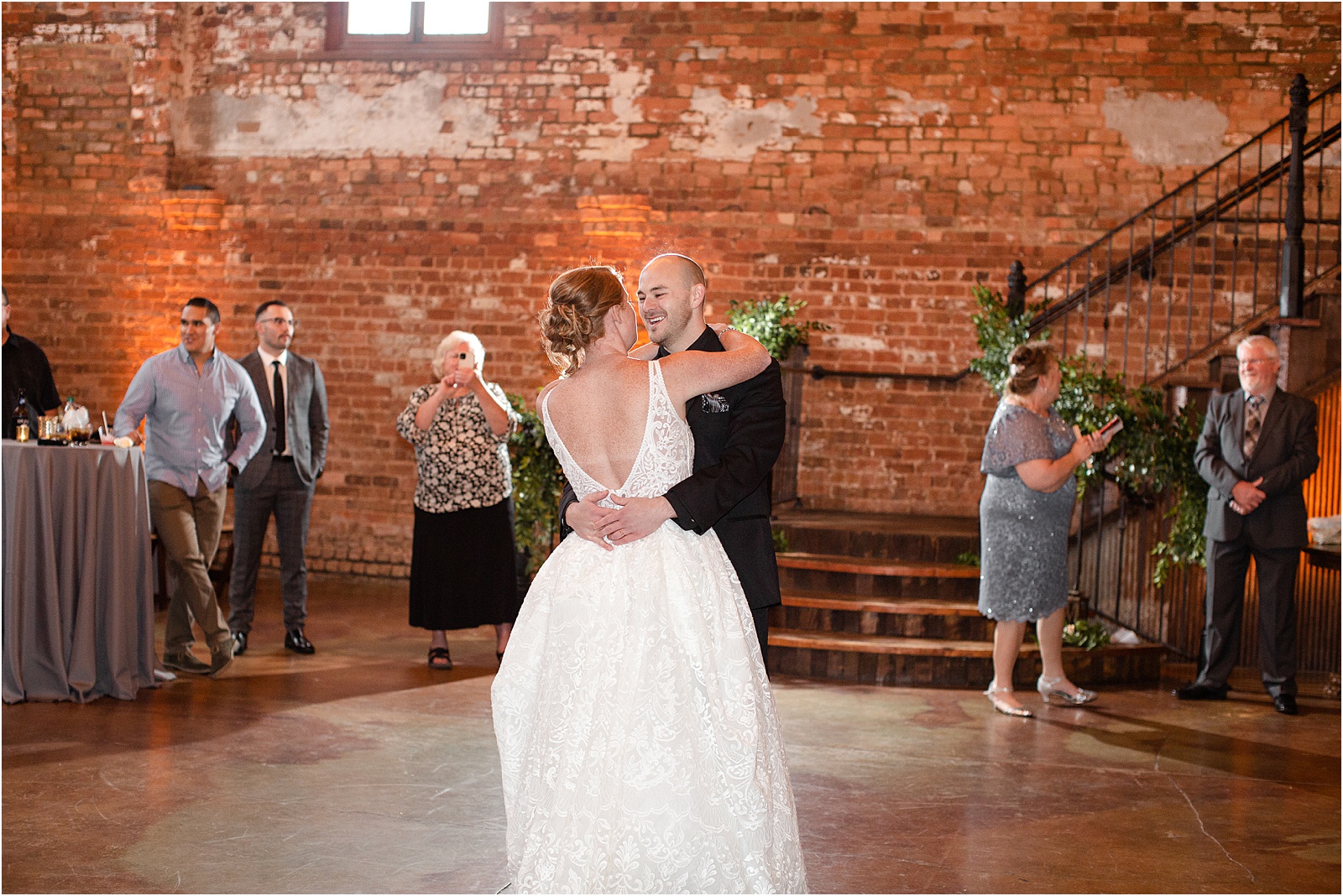 groom and bride look at each other in brick warehouse in downtown Greenville
