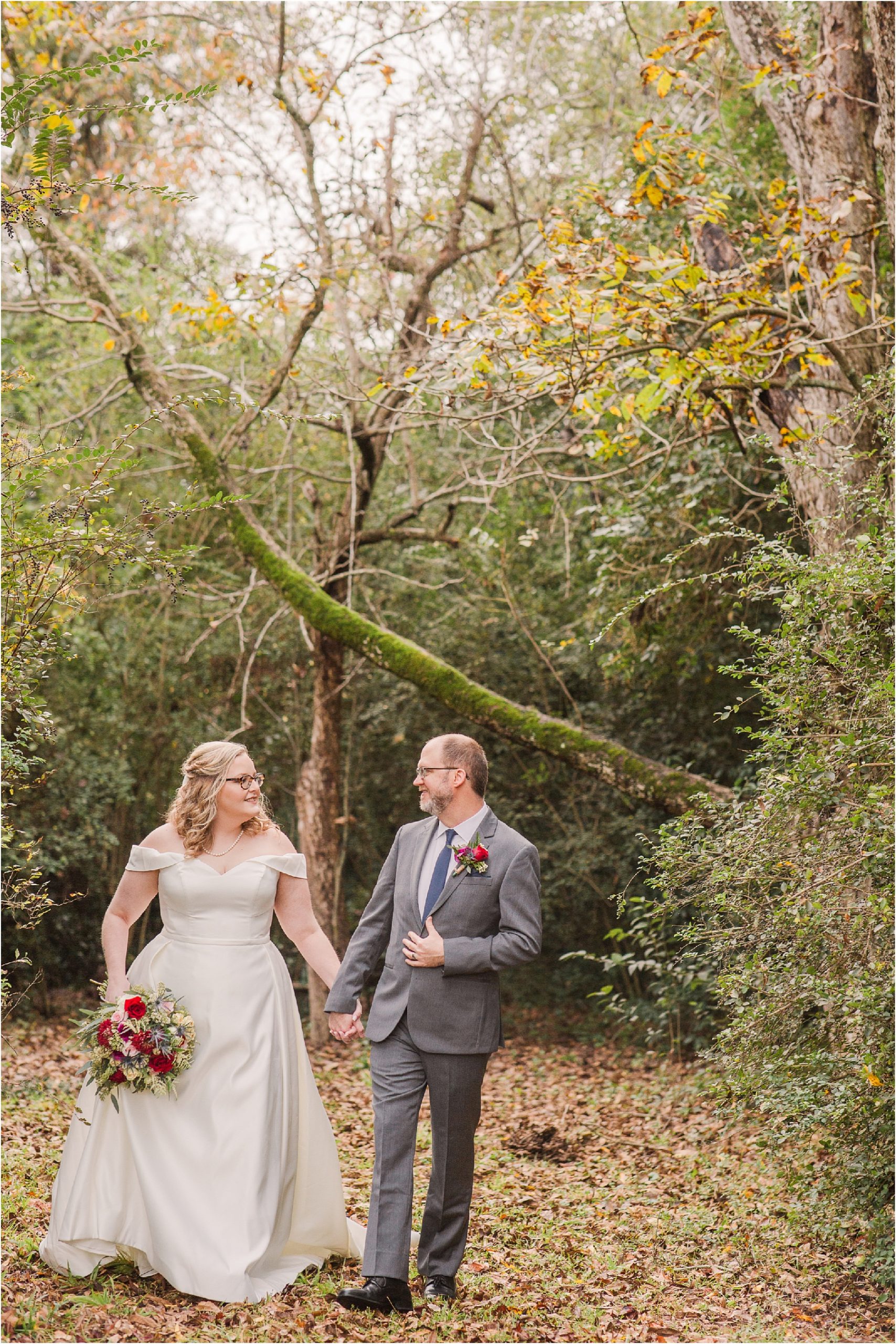 newlyweds in wedding attire walk in the woods in levonia GA