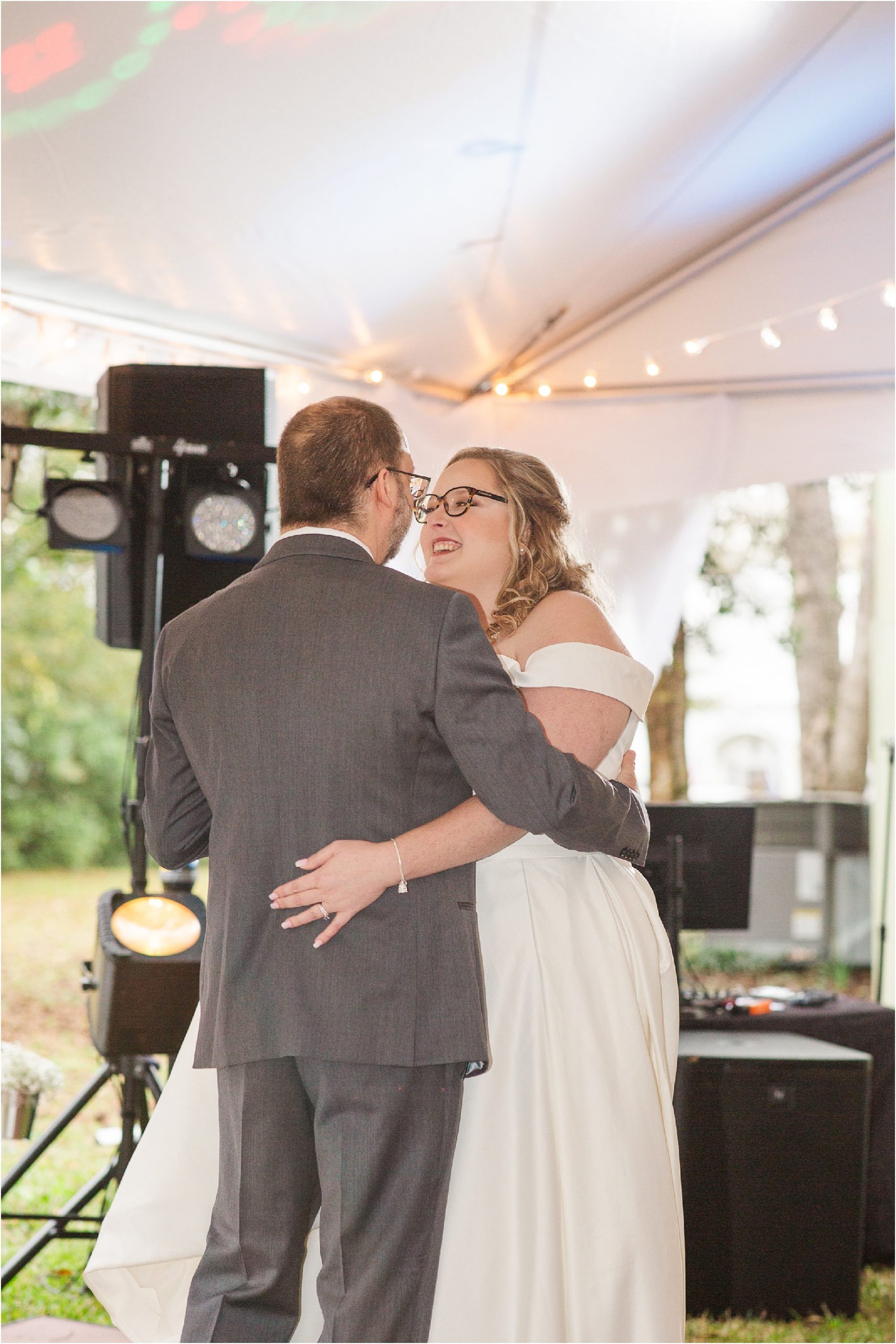 bride and groom share first dance under white tent outside
