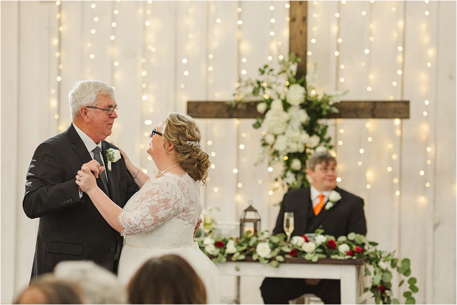 bride dances with father with groom watching
