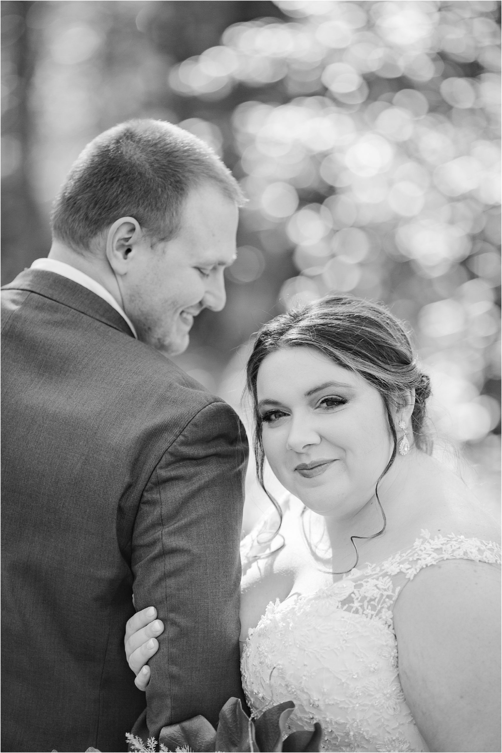 black and white photo of bride looking at camera and husband looks away