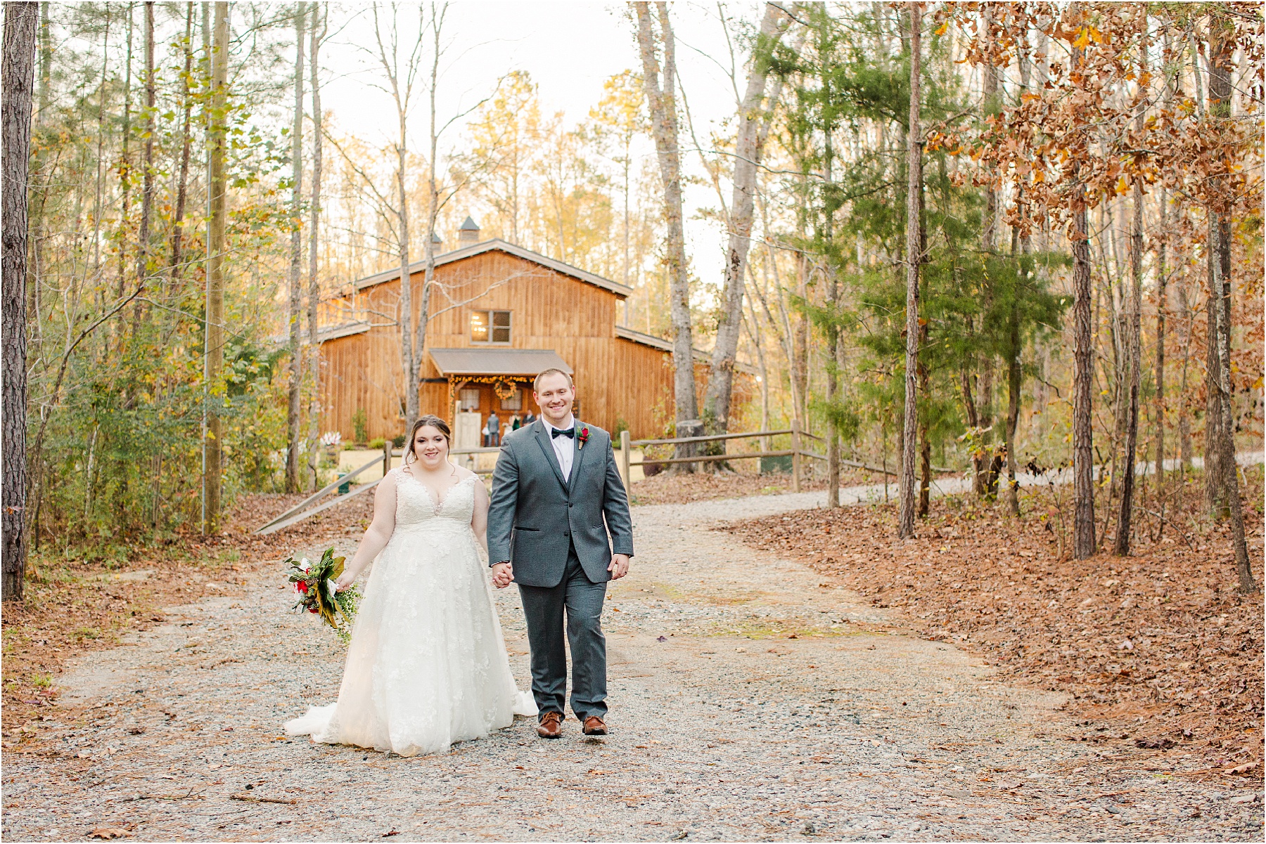 man and women in wedding attire walk towards camera with barn in background