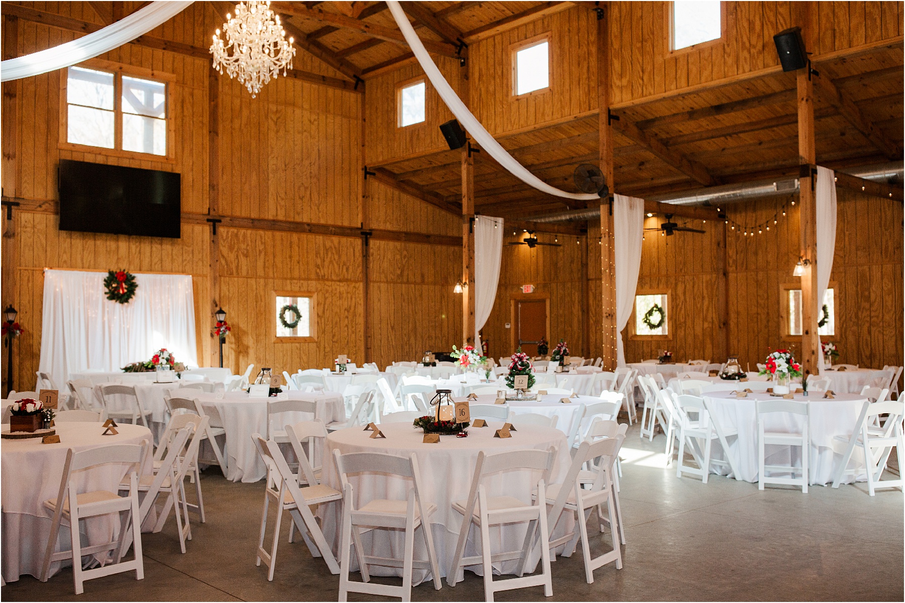 Enchanted acres inside of barn venue with white tables and chairs