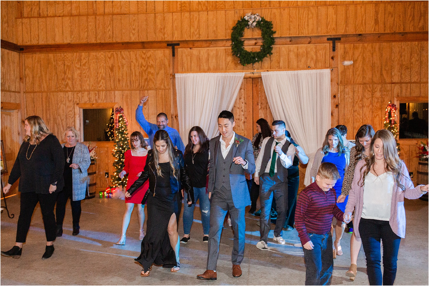 wedding guests line dancing at a barn venue