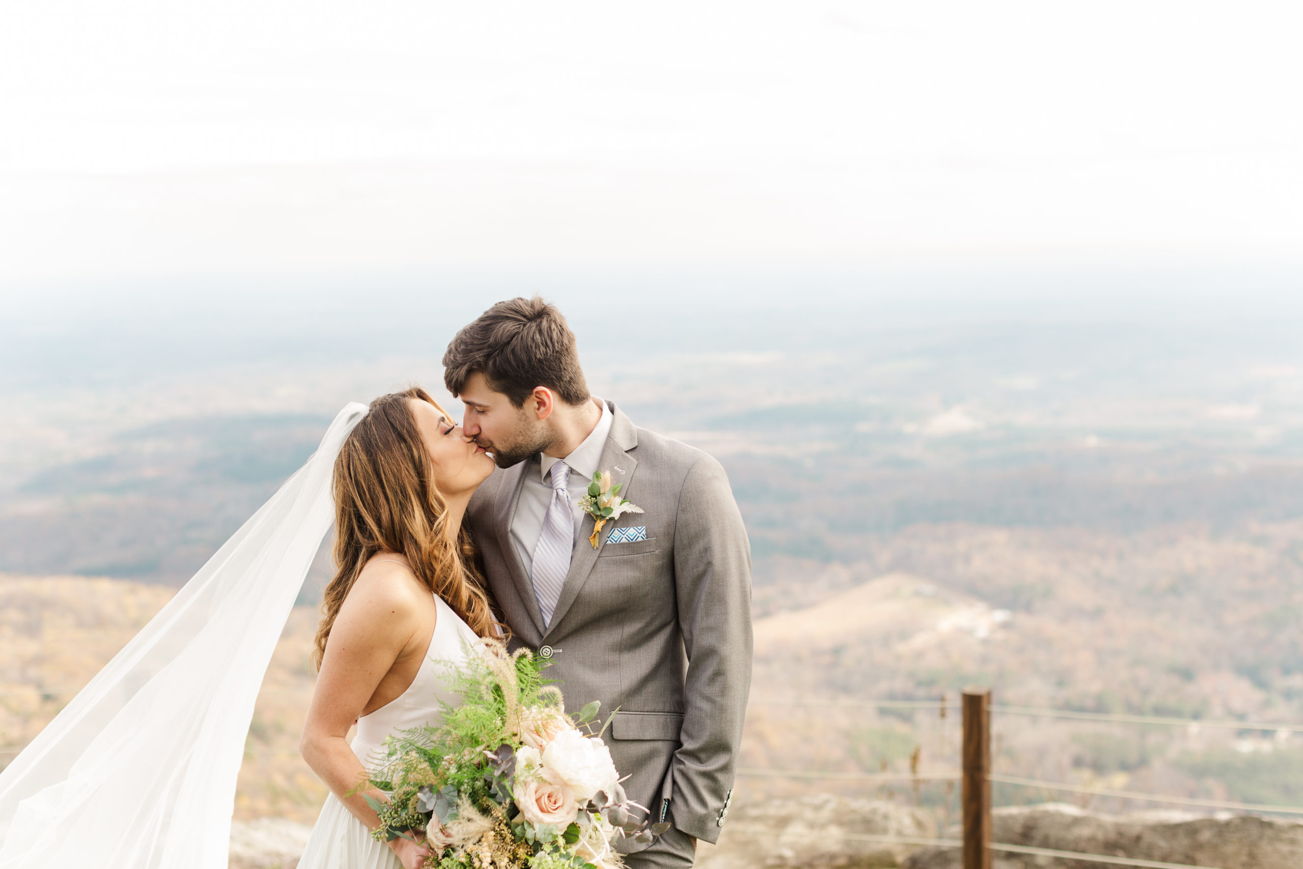 Married couple posing in front of mountains at Glass Mountain Chapel 