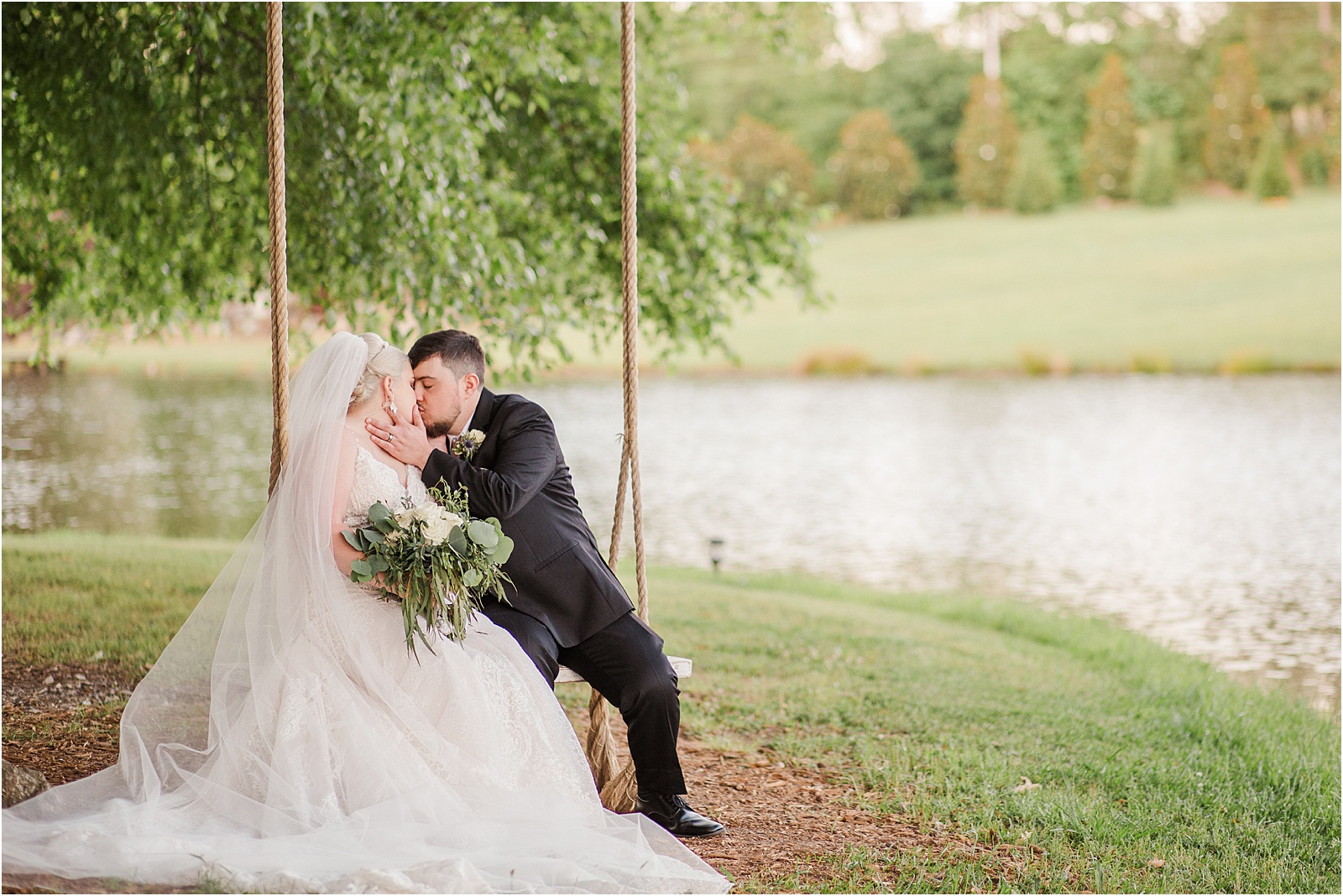 just married couple kissing in a tree swing next to a pond